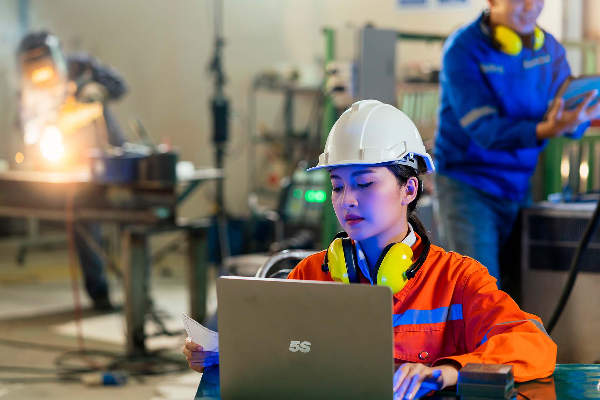 worker behind a laptop with a blueprint